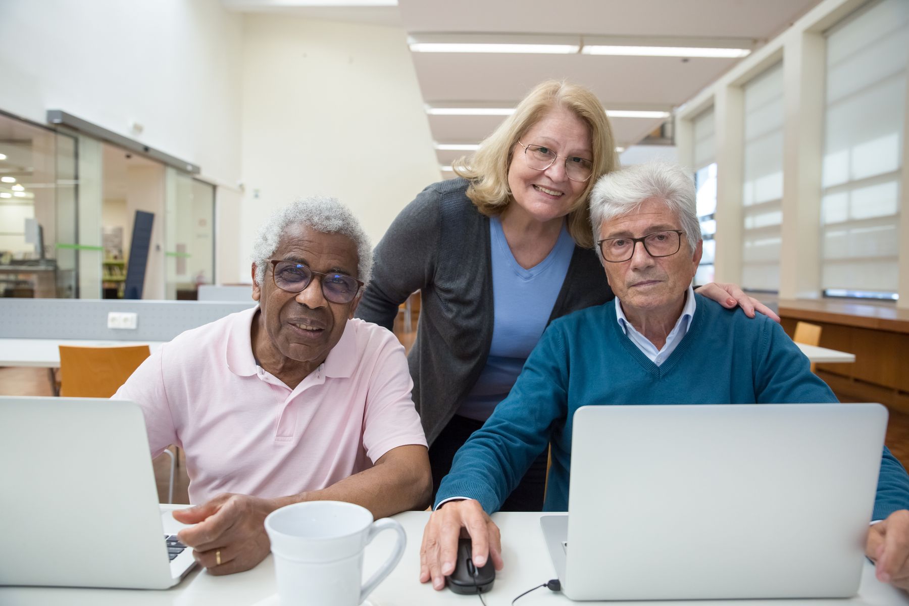 Een docent helpt senioren met de computer
